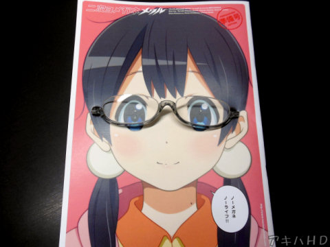 実際にメガネをかけさせてみた、前回と同じく同人誌に穴が開いているメガネは今回も付属、表紙は北白川たまこ（たまこまーけっと）